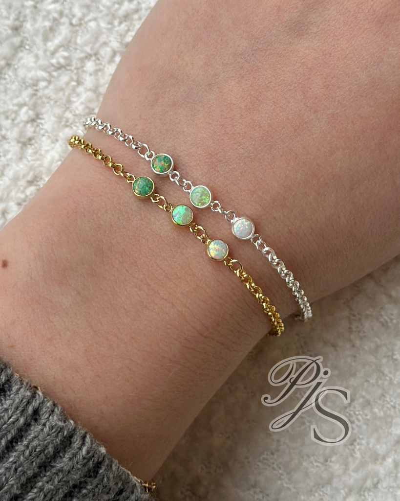 A collection of 4mm opal connectors in various colors including blue, pink, green, yellow, and colorless, attached to small gold-filled or sterling silver settings, displayed on a textured white surface.